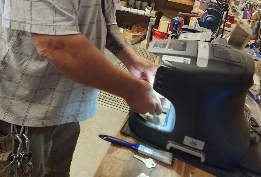Locksmith cutting a key on the machine at the St. Clair & Lee's Locksmith Plus workbench